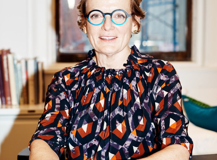 Alexandra Champalimaud at her New York design studio desk wearing blue-framed glasses and patterned shirt