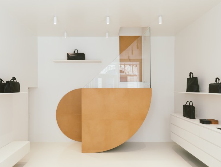 Isaac Reina's Paris shop interior with minimalist white walls, angular leather tabletops, and displayed black leather bags.