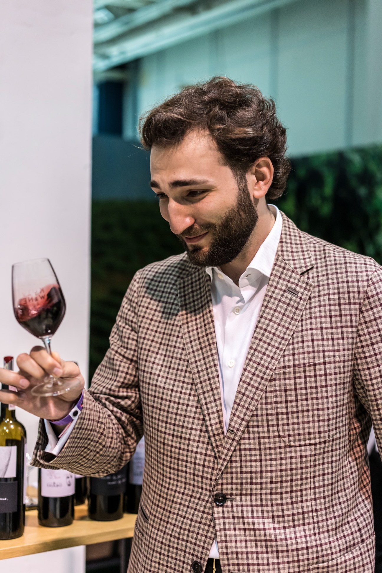 Man in checked blazer swirling a glass of rosé wine at Kyiv Wine fair