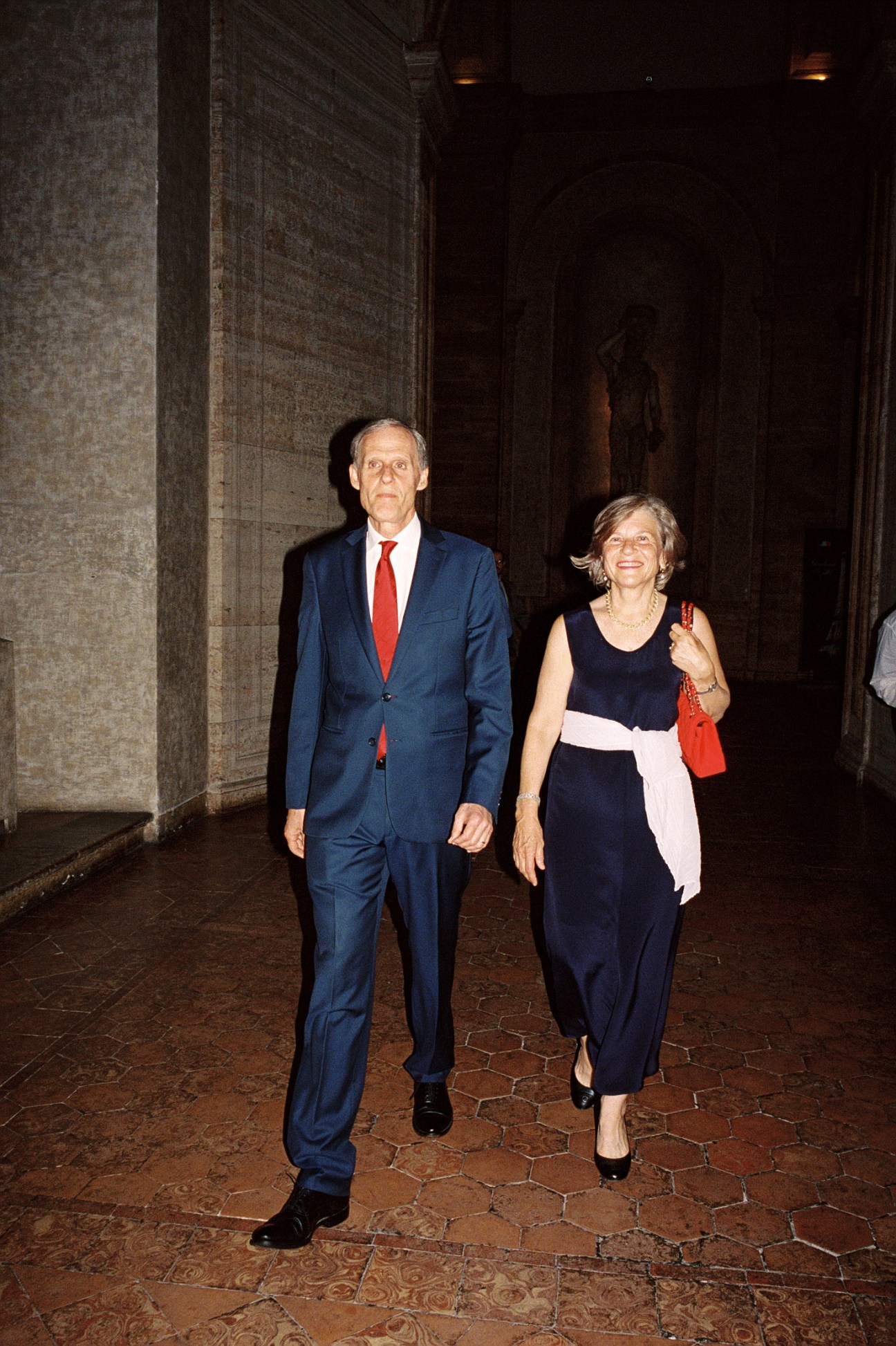 French Ambassador Christian Masset and his wife Hélène walking through a stone corridor at Palazzo Farnese.