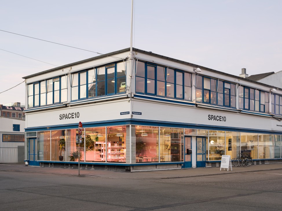 Space10 office building exterior in Copenhagen's Meatpacking District, featuring blue-framed windows, white facade, and ground-floor retail space.