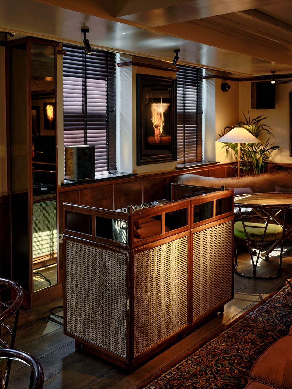 Custom rattan DJ booth with curved design in a warmly lit piano room setting