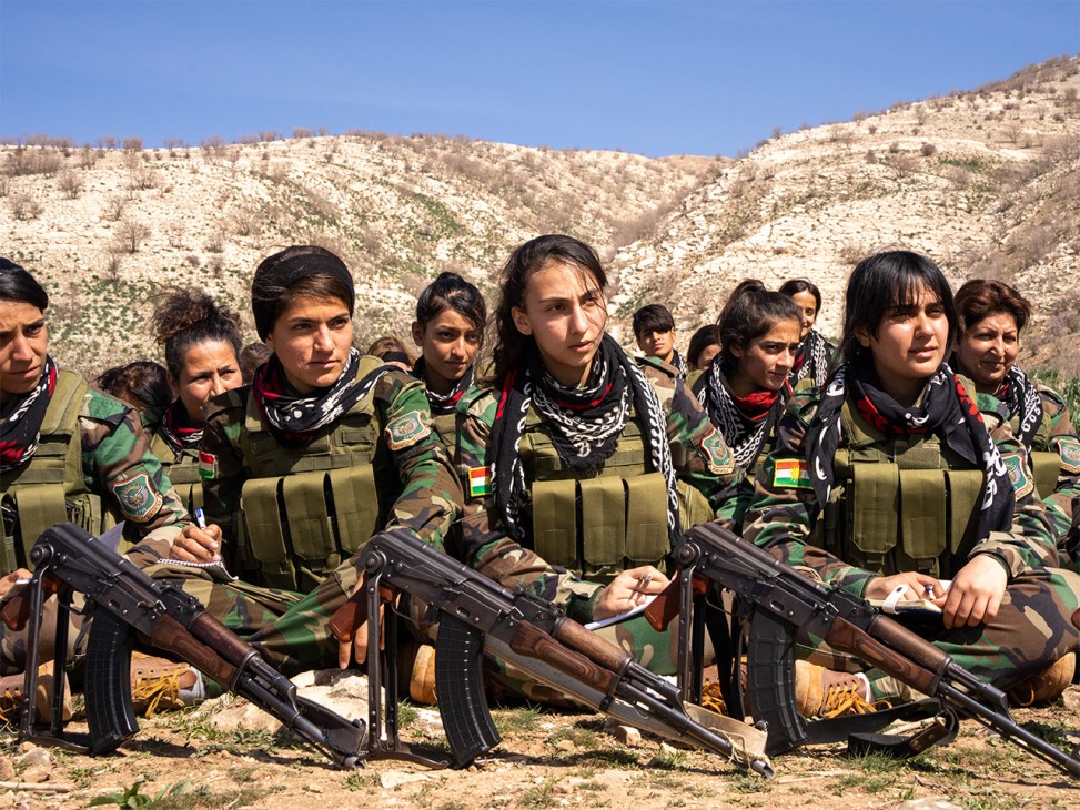 PAK women's battalion members standing at attention in green fatigues at their mountain camp