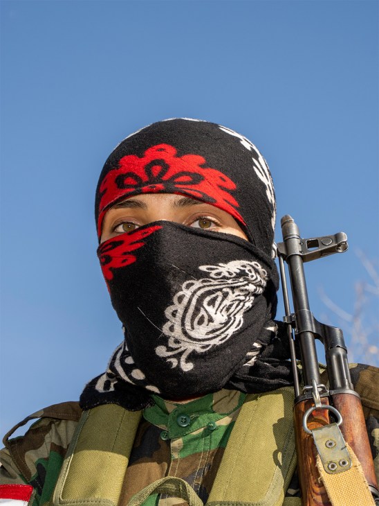 Kurdish fighter in camouflage uniform standing outdoors