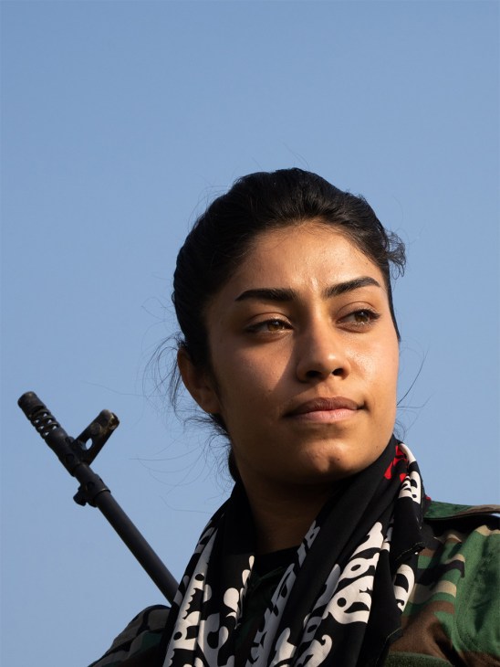 Portrait of a young Kurdish female fighter in military fatigues