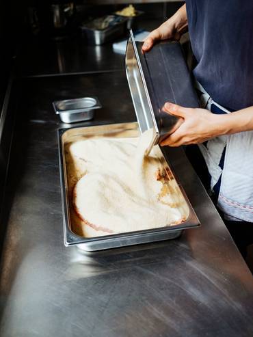 A sauce being poured into a metallic container.
