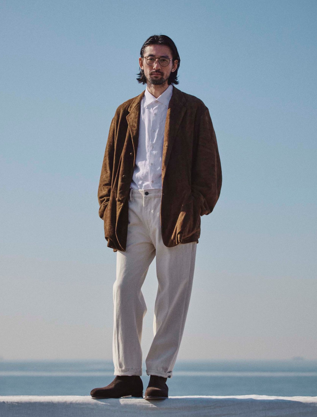 Jacket by Comoli, shirt by Glanshirt, trousers by Emporio Armani, boots by JM Weston, glasses by Mykita