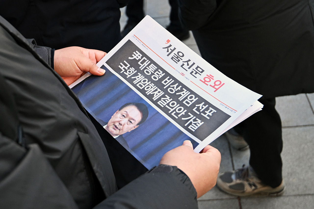 A man reads an extra edition newspaper in downtown Seoul on December 4, 2024, after martial law was lifted. South Korean President Yoon Suk Yeol abandoned a short-lived attempt at martial law on December 4, after lawmakers defied security forces to vote against his declaration and thousands of protesters took to the streets.