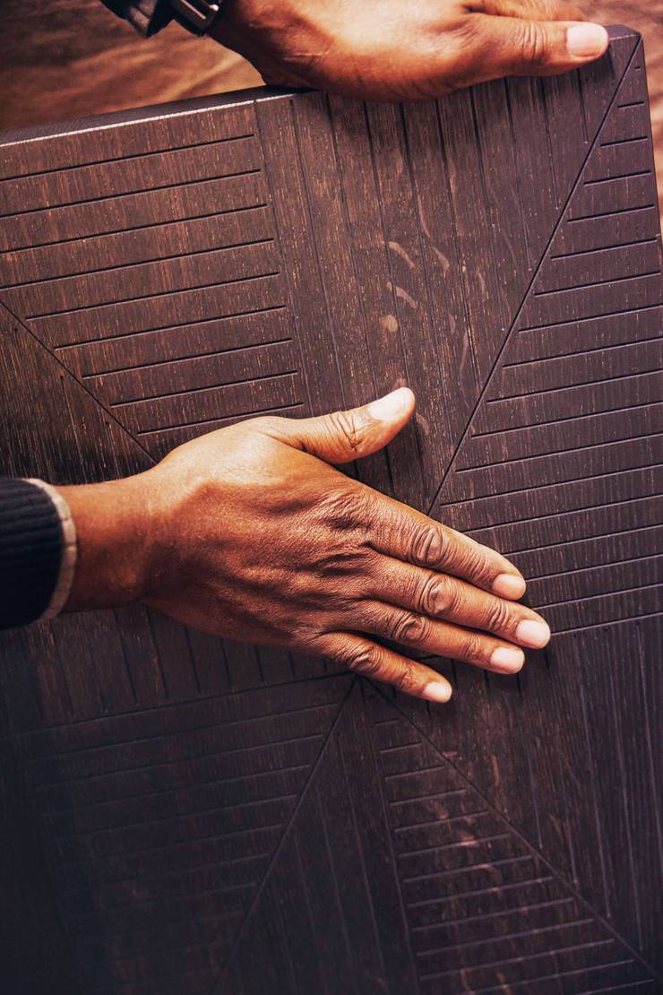 A hand touching a wooden object.