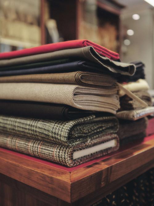 A stack of fabris positioned on a mahogany table.