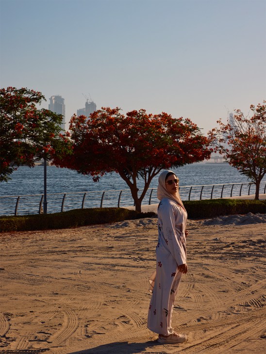 A woman standing in front of colourful 'flame trees' in Dubai