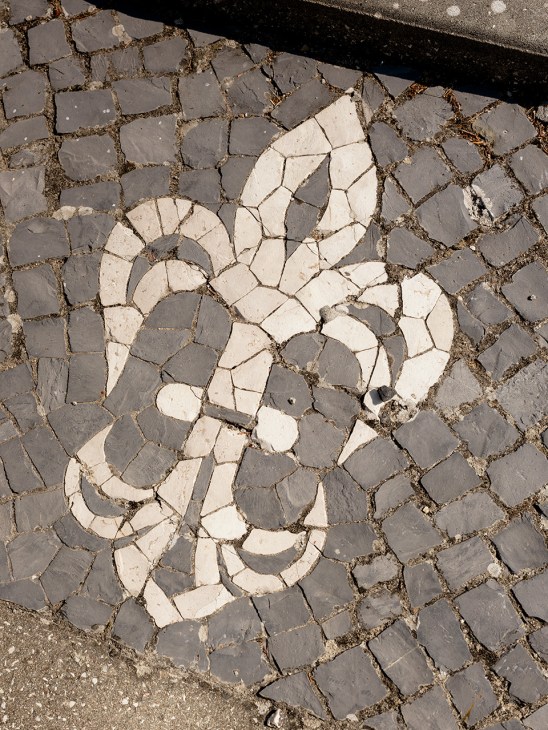 Decorative stone pavement pattern with white and gray limestone tiles arranged in a symmetrical motif by artisan Vítor Graça.