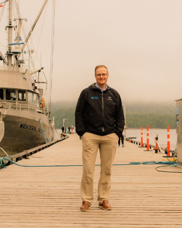 Kurt Slocombe, CEO of Prince Rupert Port Authority, standing on a wooden dock beside a large ship.