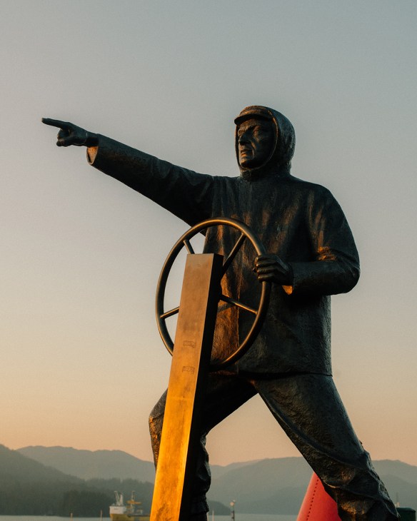 Bronze statue of a sailor at the helm pointing outward in Mariner's Memorial Park, Prince Rupert.