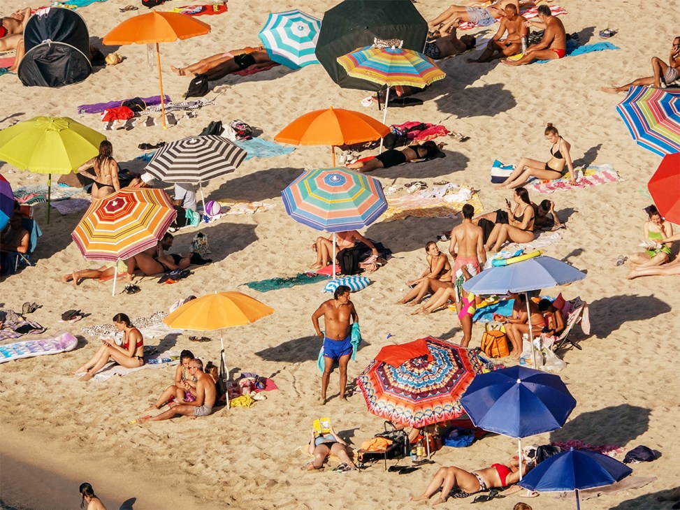 Beachgoers under umbrellas on the sand