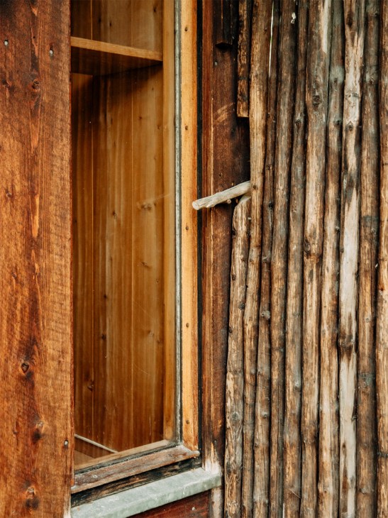 Weathered wooden entrance door with metal handle against aged timber cladding
