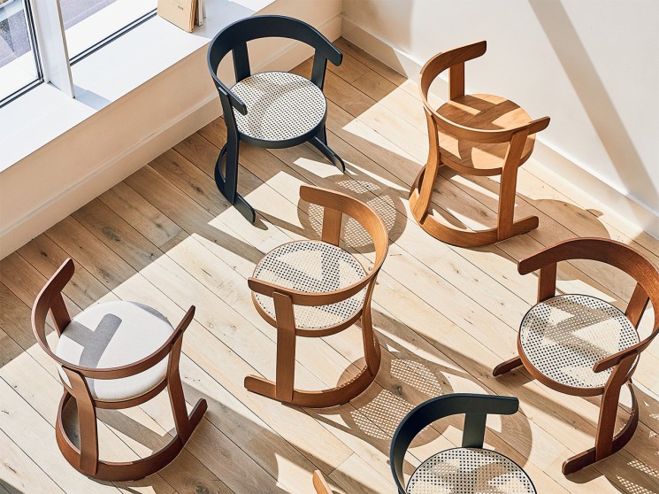 Collection of modern and vintage chairs displayed in a bright showroom with wooden floors and natural lighting.