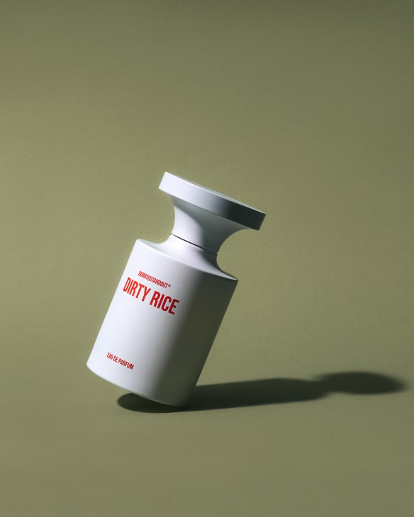 Borntostandout Dirty Rice eau de parfum bottle with white cylindrical design and red text on sage green background