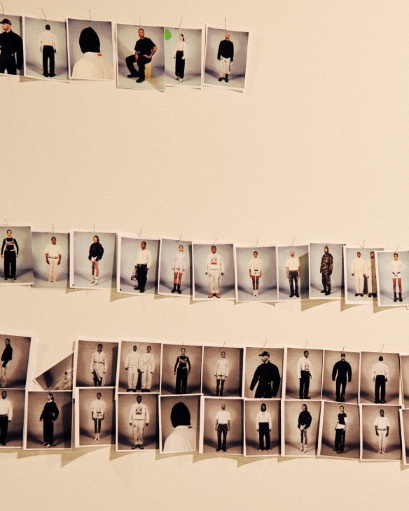 Multiple polaroid-style model photographs pinned to a beige wall displaying people wearing streetwear and fashion pieces.