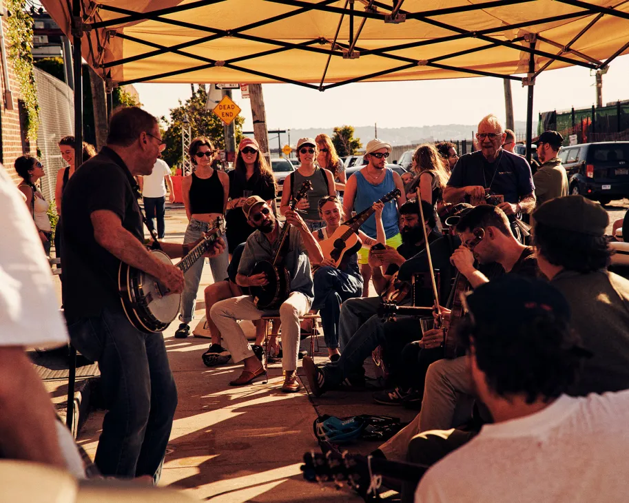 Musicians and spectators gather under a yellow canopy for live music at Sunny's Bar in Red Hook.