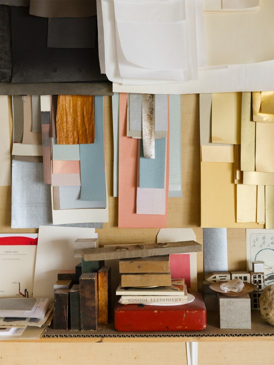 Decorative paper samples in various colors displayed on a shelf at Kamisoe studio.