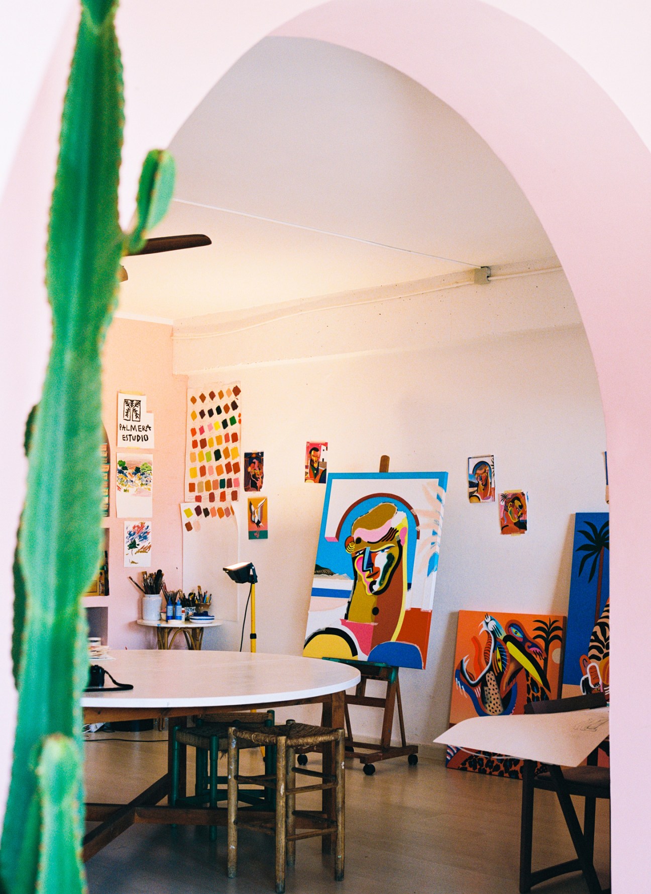 Interior view of Palmera Estudio showing arched doorway, colorful artwork, easels, and creative workspace