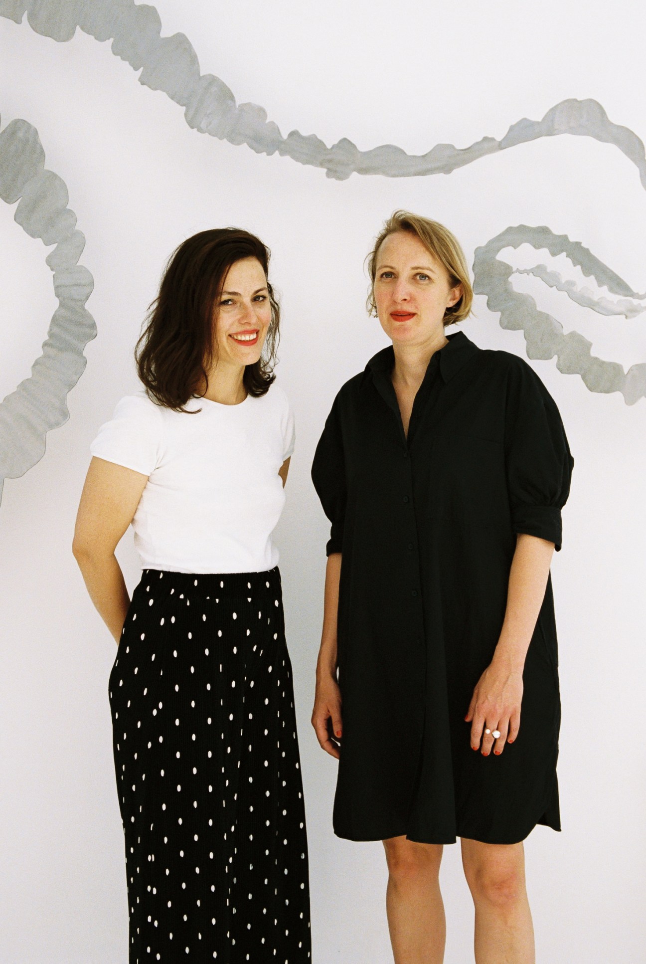 Isabella Ritter and Katharina Schendl standing together in front of a white wall with gray artwork