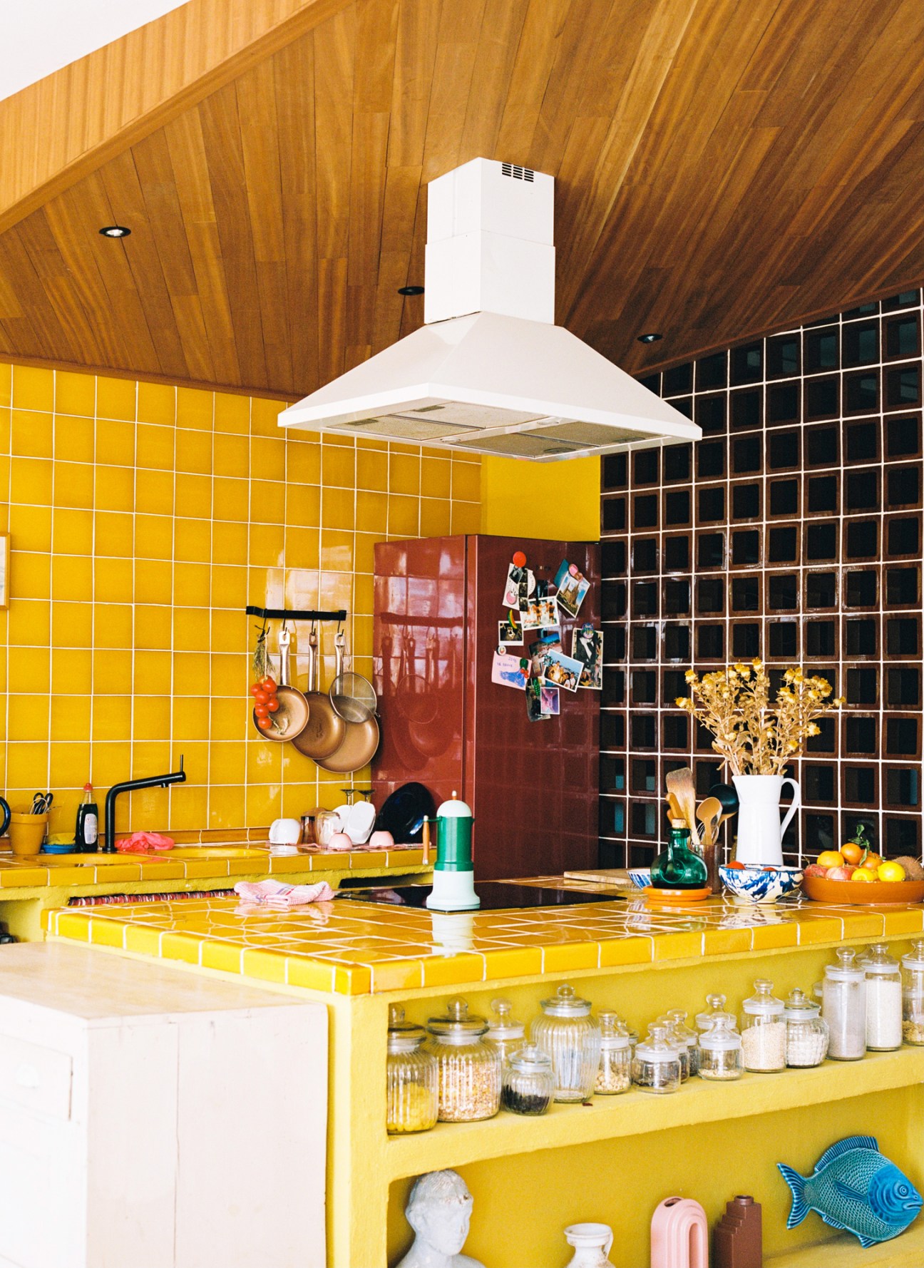 Kitchen featuring bright yellow tile countertops and backsplash with white range hood and wooden ceiling