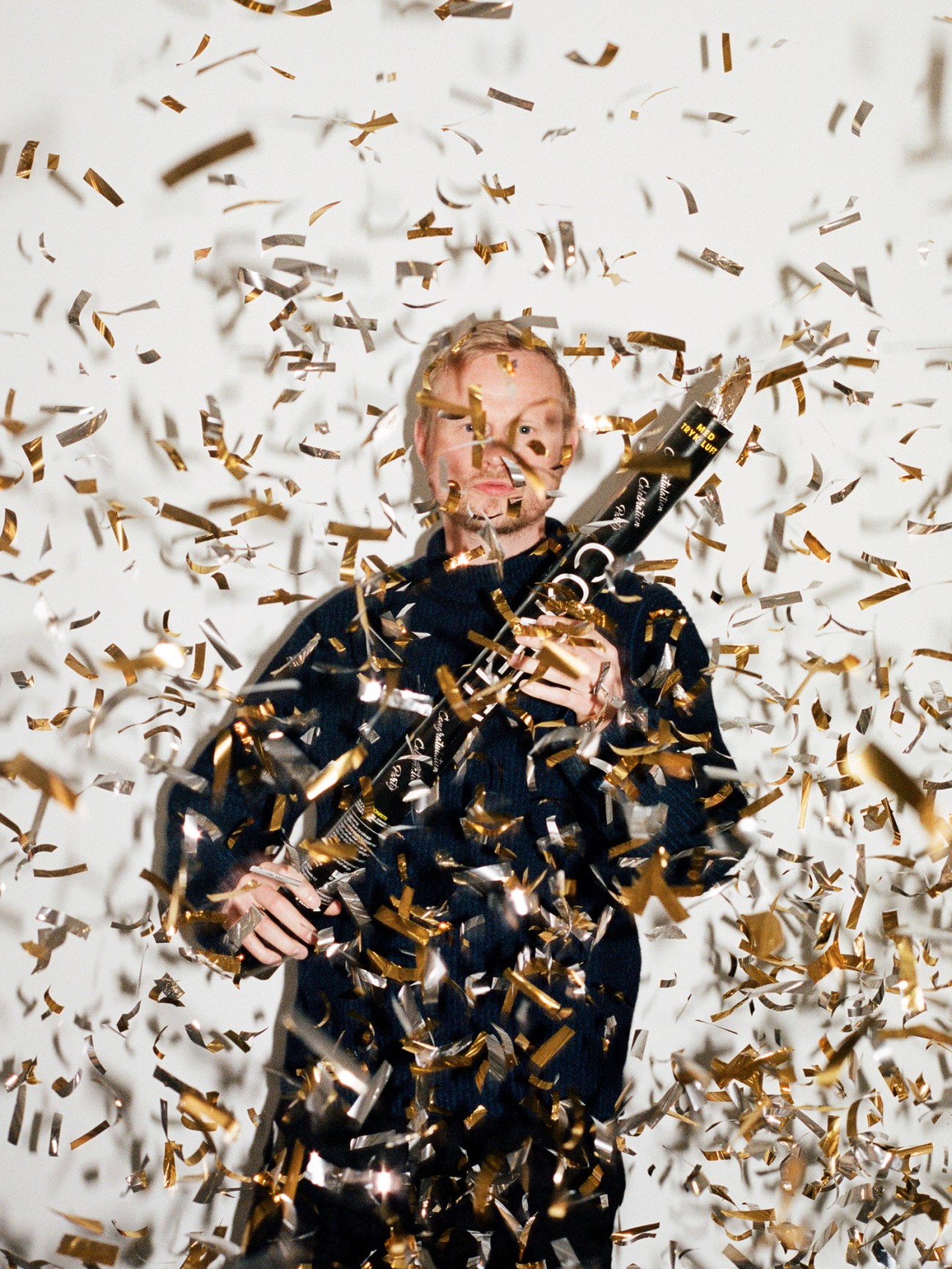 Jonatan Spang surrounded by falling golden confetti against a white background