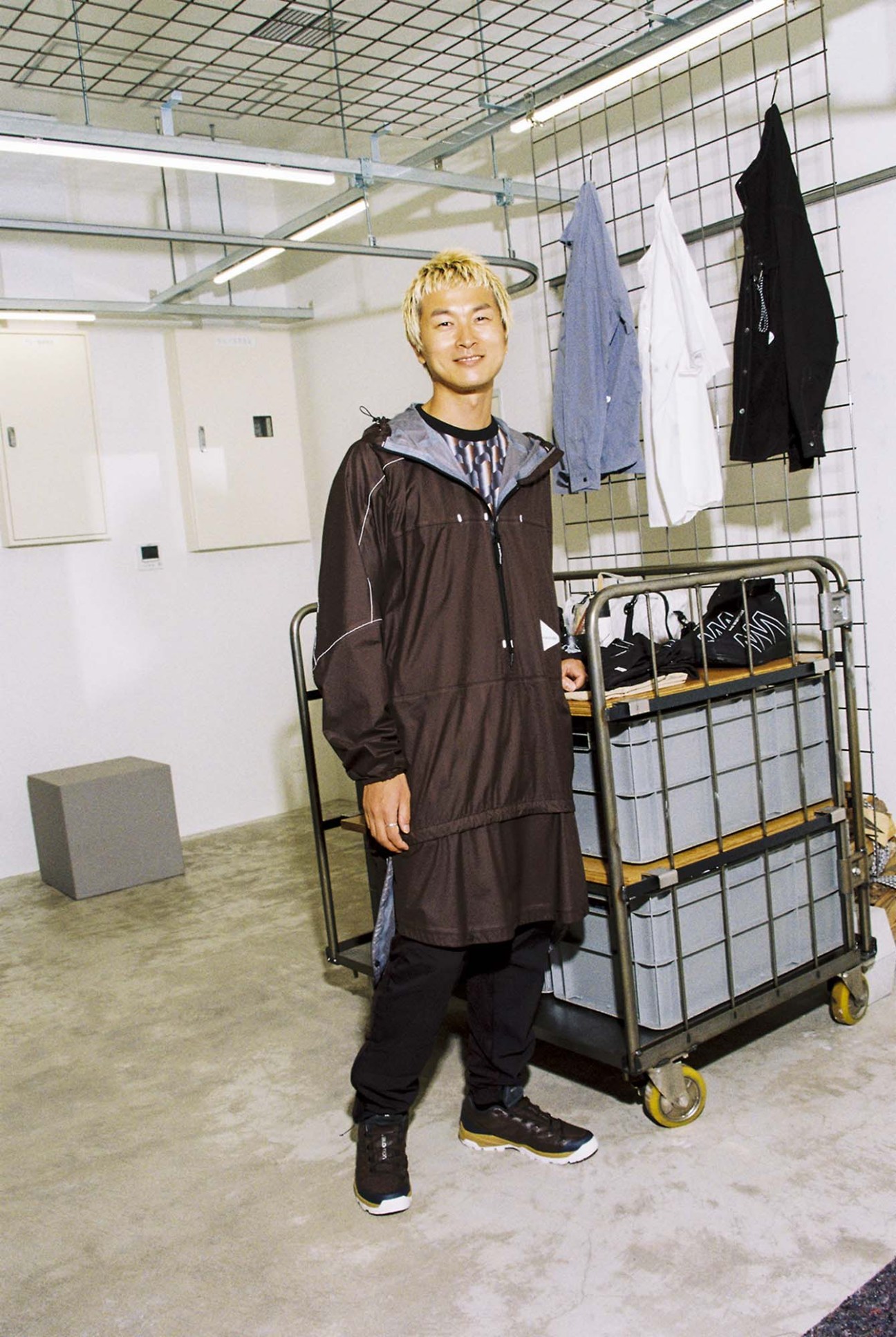 Kento Tada wearing oversized And Wander mountaineering jacket and black trousers in a Shibuya shop