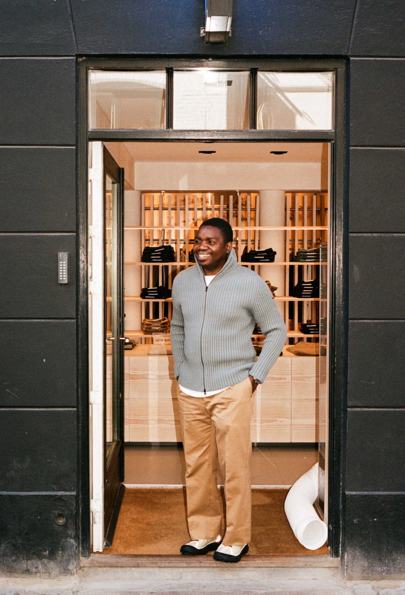 Kevin Kafesu, head buyer at Norse Projects, standing in doorway of Copenhagen menswear store