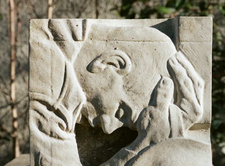 Stone relief carving showing a figure with raised hands looking upward