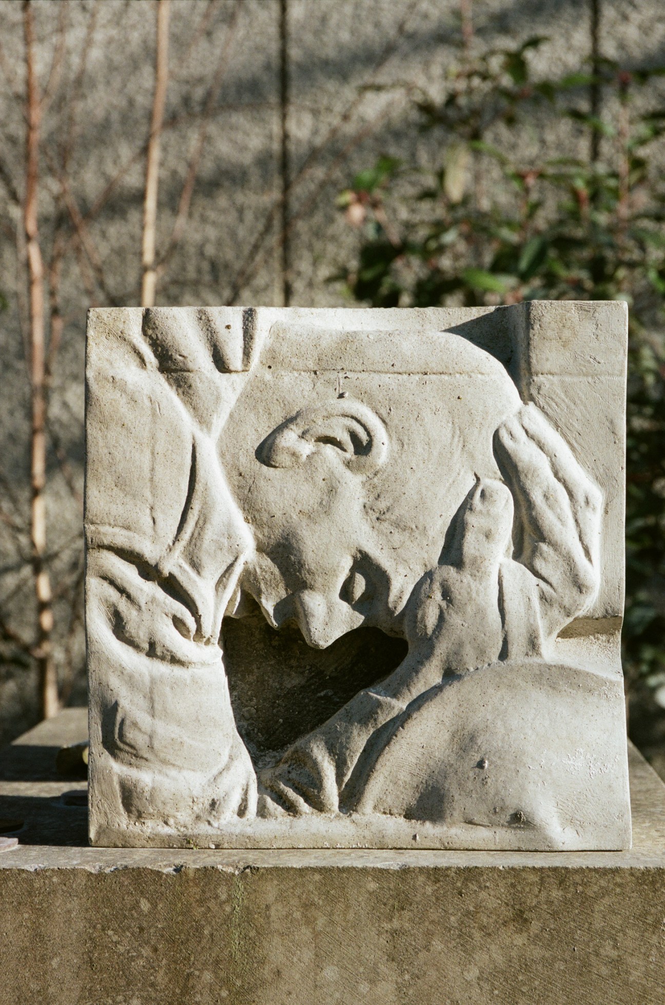 Stone relief carving showing a figure with raised hands looking upward