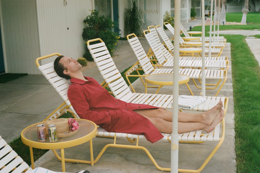 Woman in red dress relaxing on white and yellow striped lounge chair on covered patio.