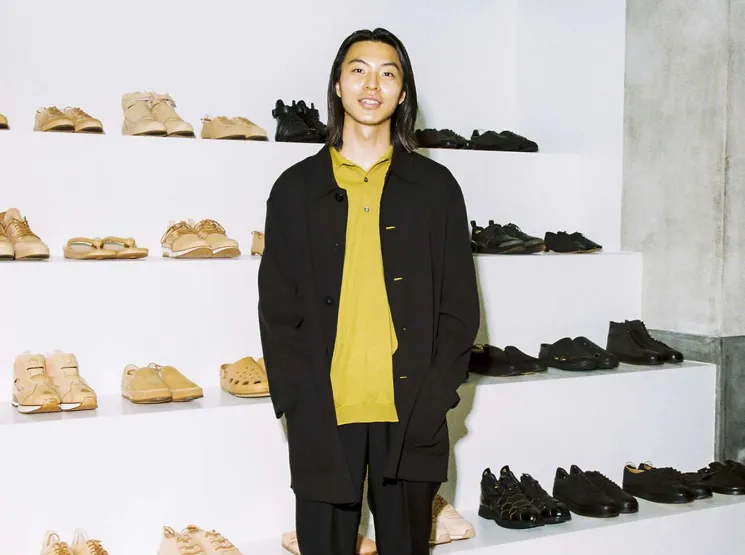 Toga Ikeda standing in Hender Scheme store with shoes displayed on shelves behind him
