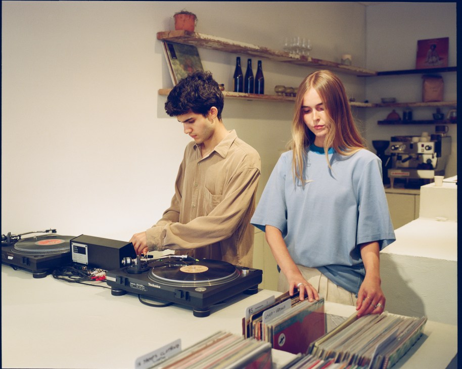 Two people browsing vinyl records at a counter with a turntable