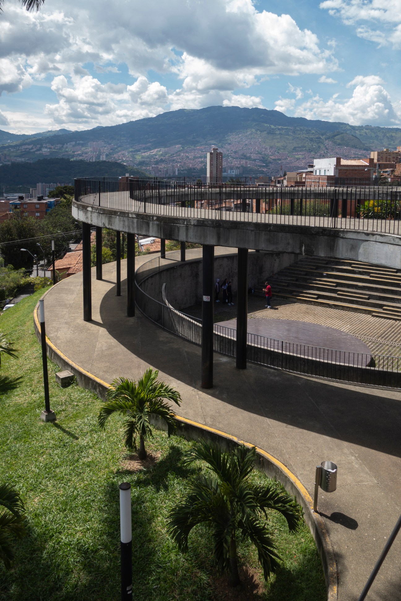 Curved concrete walkways and amphitheater-style seating in an urban hillside setting with city views