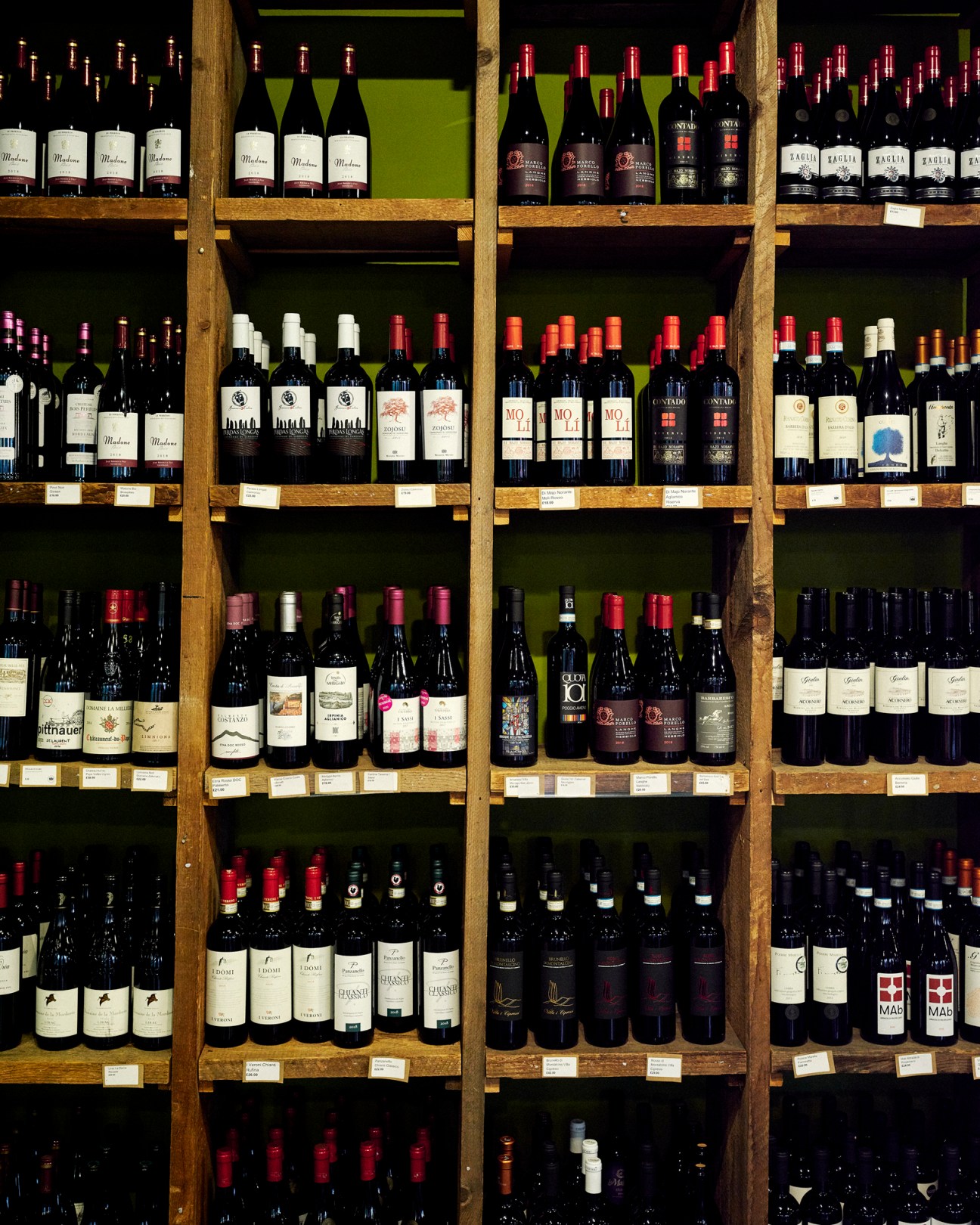 Wine bottles arranged on wooden shelves displaying various labels and vintages