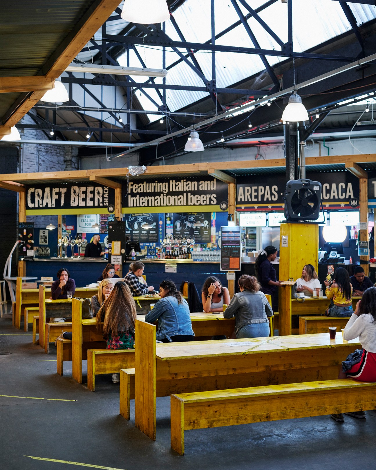 Indoor food market with wooden seating, industrial ceiling, and craft beer stalls at Mercato Metropolitano
