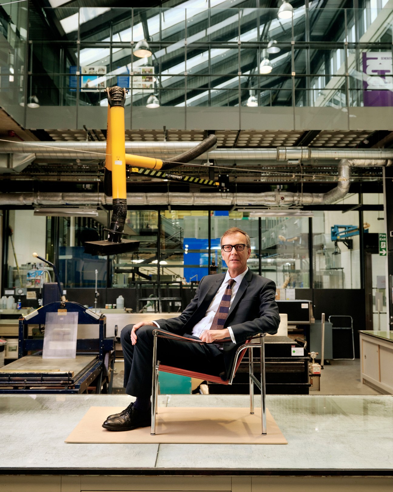 Paul Thompson seated in an LC1 armchair in the Royal College of Art print-making hall