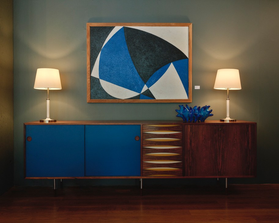 Mid-century modern wooden sideboard with blue cabinet doors and geometric abstract artwork above