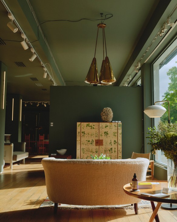 Modern gallery interior with green walls, contemporary furniture displays, and large windows in London showroom