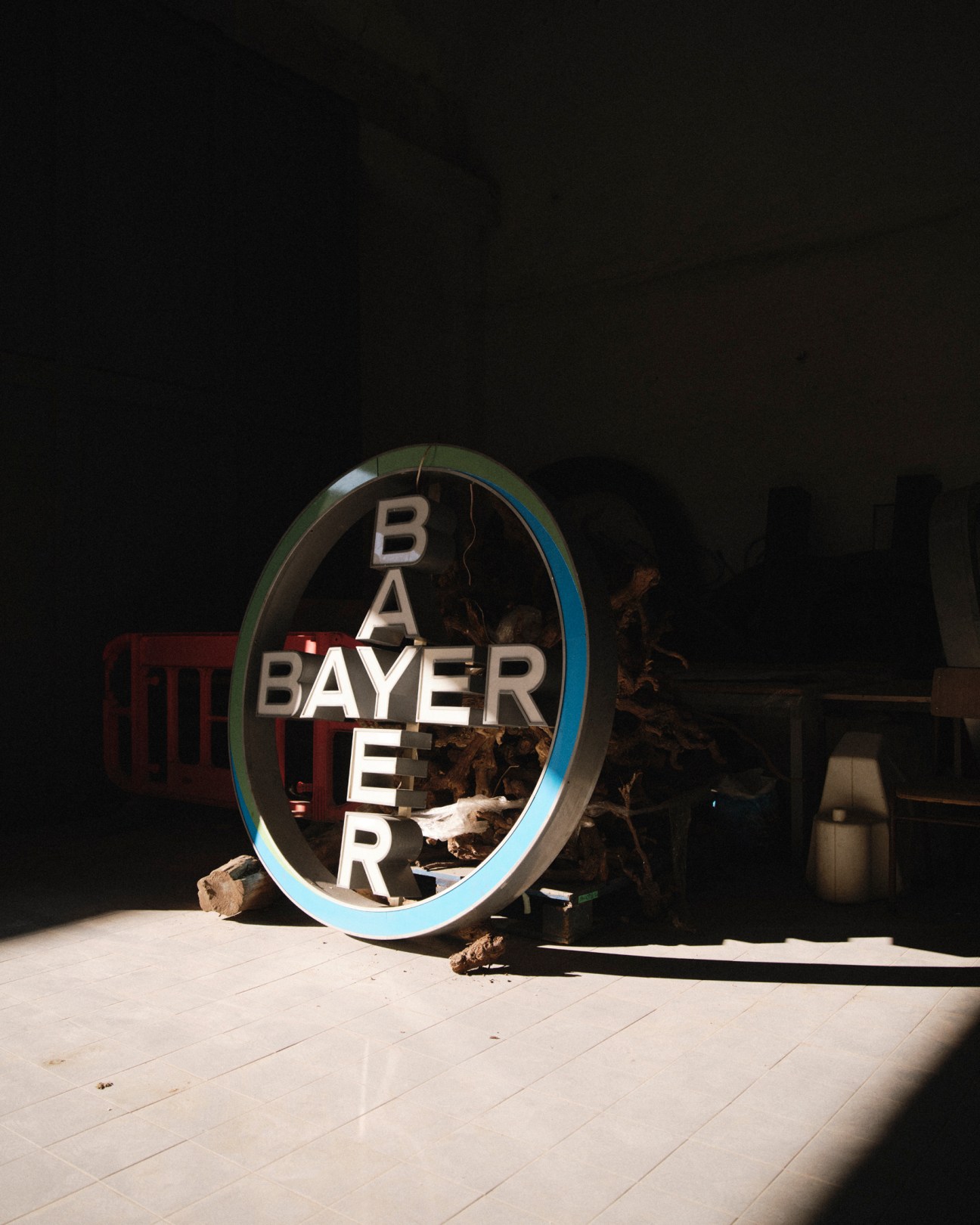 Large neon glasses sign with blue trim sitting on tiled floor in dark warehouse space