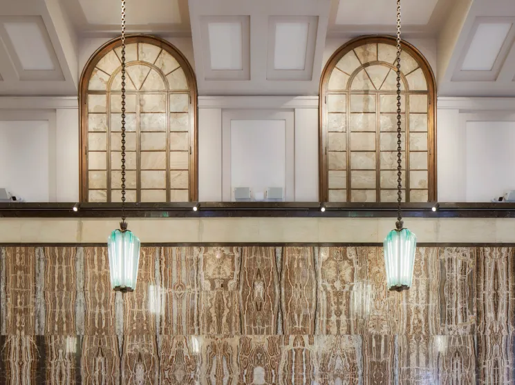 Art deco interior detail showing brass lettering and marble wall fixtures from the original 1940s banking hall design