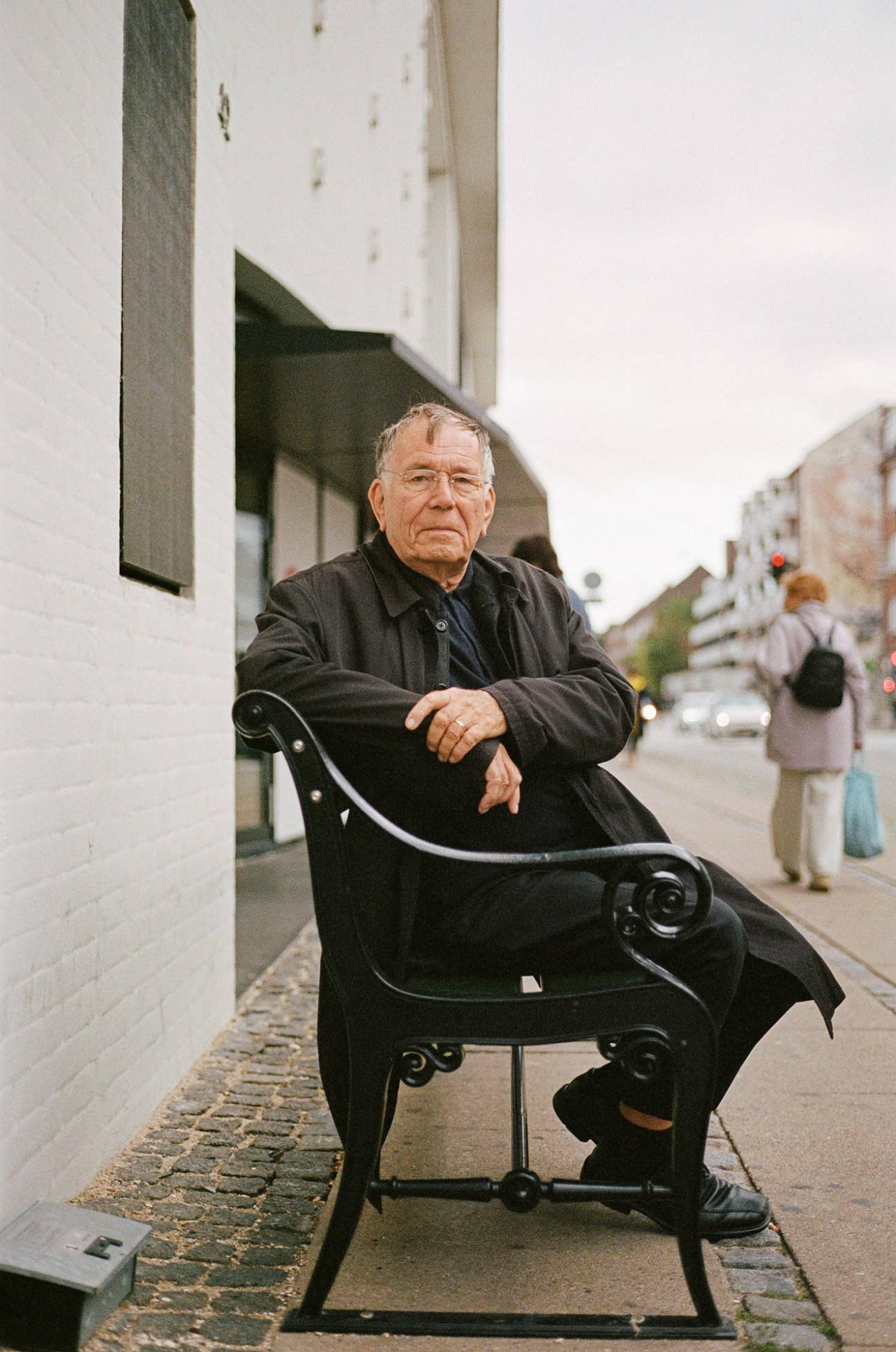Jan Gehl sitting on a traditional Copenhagen city bench with cast iron handles near Vanløse station