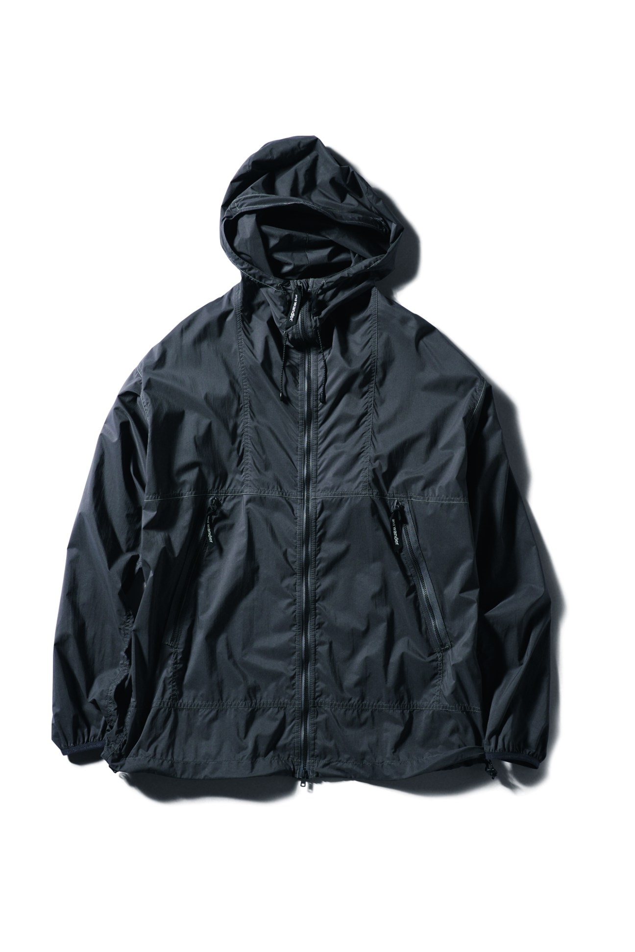 Dark navy parka by And Wander with hood, front zipper and chest pockets on white background