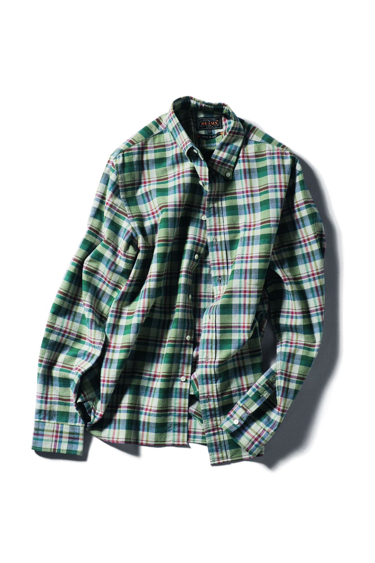 Green and multicolored plaid flannel shirt by Beams Plus laid flat against white background