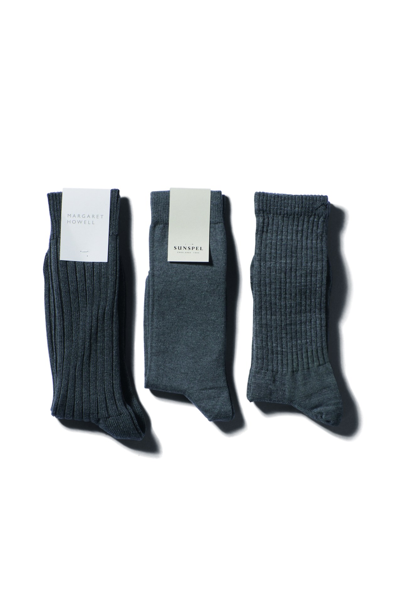 Three pairs of navy blue ribbed socks with Margaret Howell and Sunspel labels displayed on white background