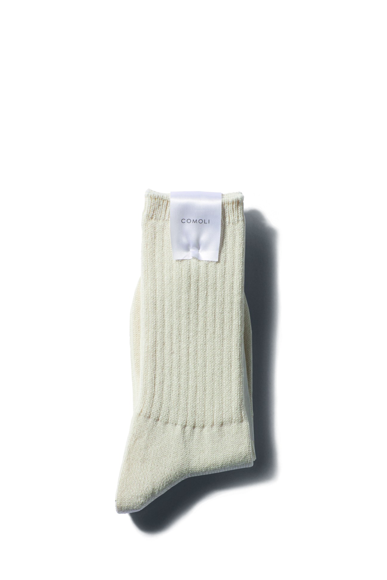 Light green ribbed crew socks with white label band displaying Comoli brand name