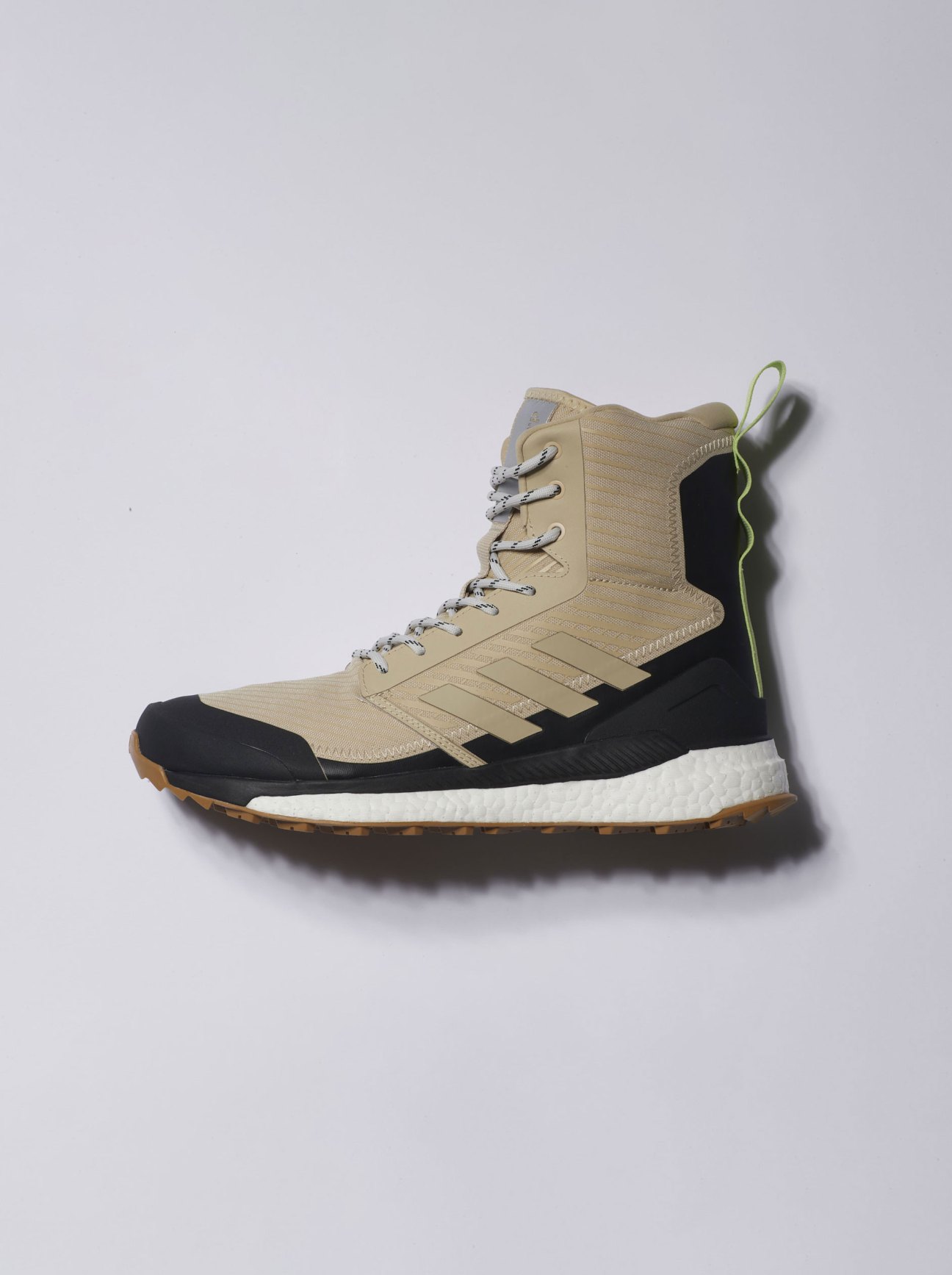 Adidas Terrex hiking boots in beige and black with white sole against gray background